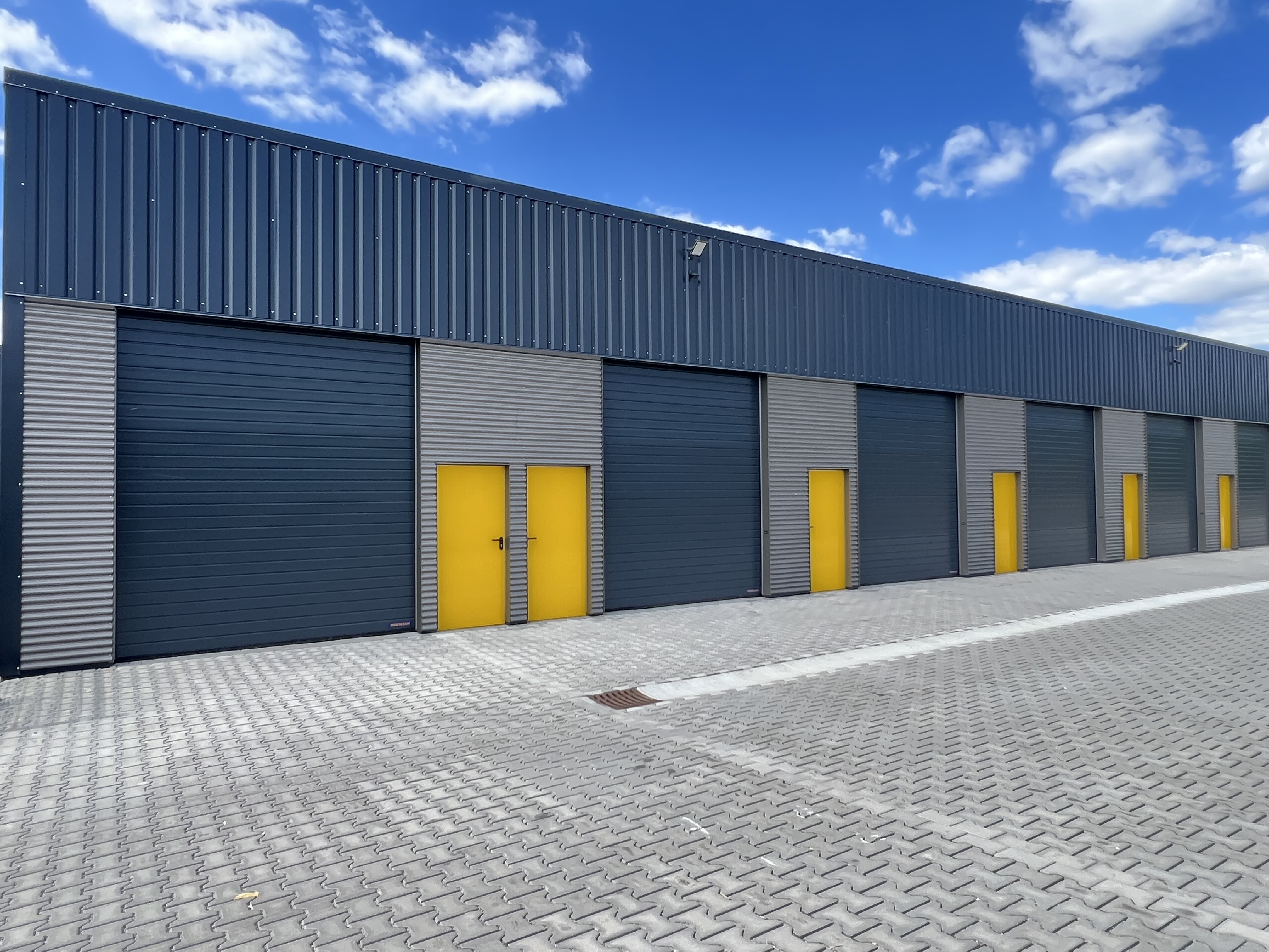 Garagen und Lagerhalle deinlager.com in Neukirchen vorm Wald – Außenansicht mit anthrazitfarbenen Garagentoren und gelben Eingangstüren